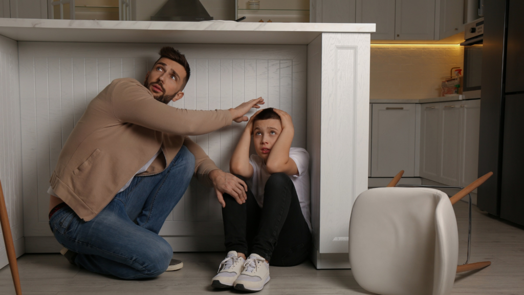 Father and his son hiding under table in kitchen during earthquake