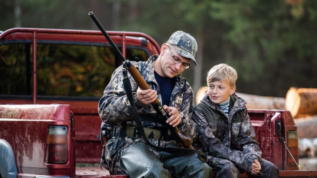 Dad showing boy mechanism of a shotgun rifle
