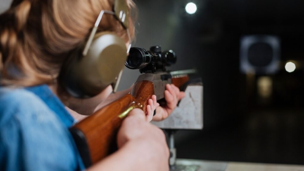 a girl firing a rifle in a shooting range
