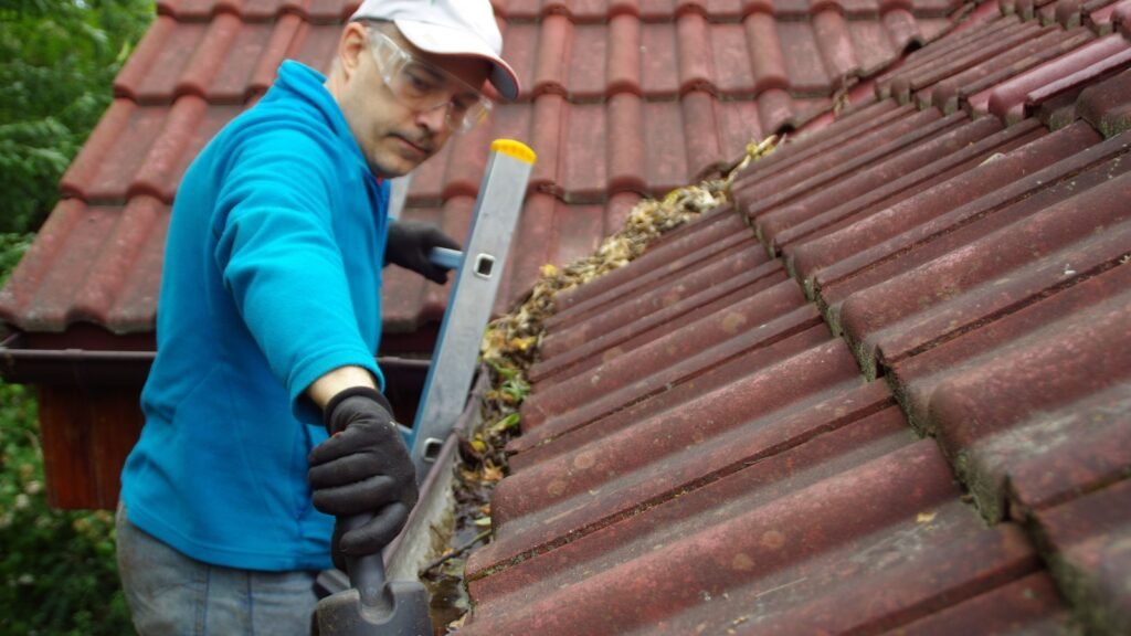 a man on a ladder cleaning the gutter