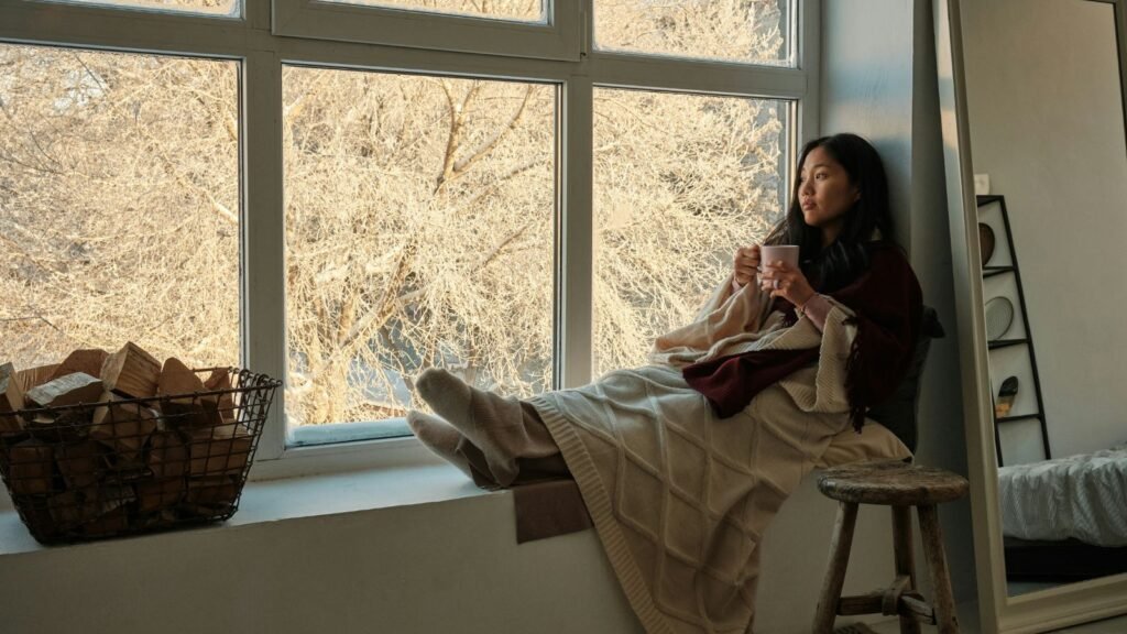 woman beside window holding a cup of coffee