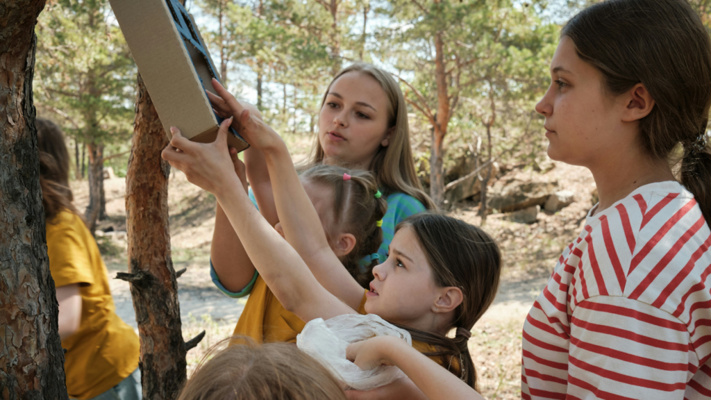 a group of children hanging a bird feeder